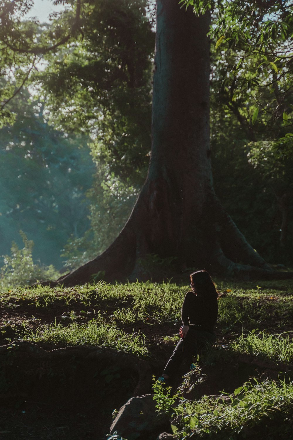 woman in black jacket standing beside tree during daytime