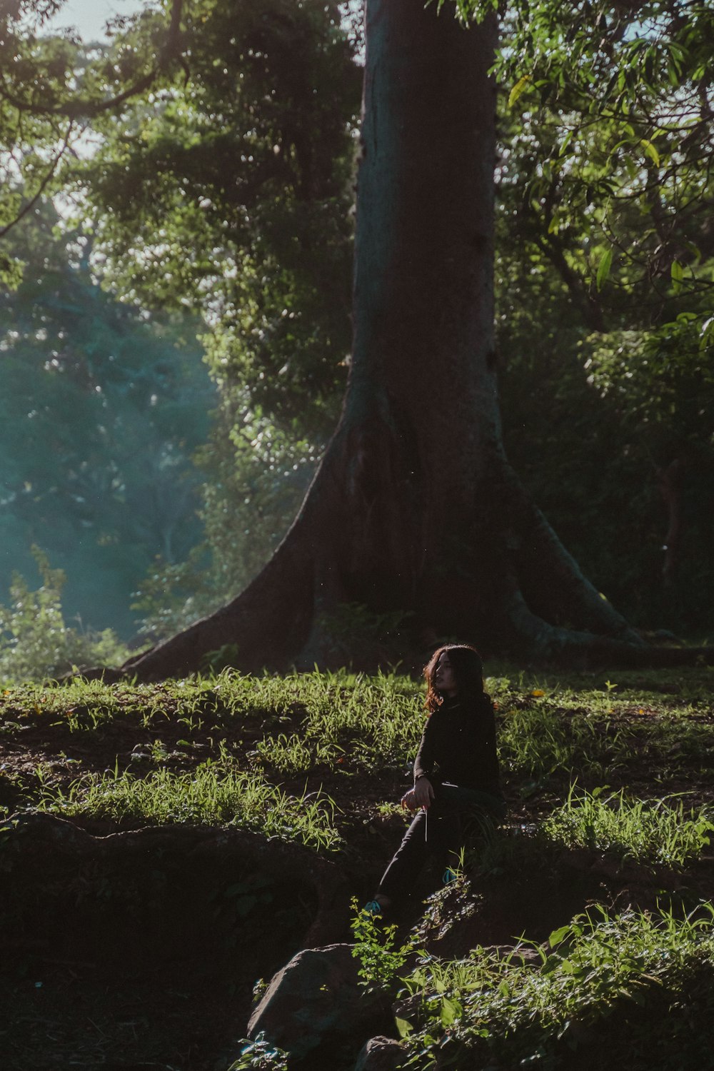 woman in black jacket standing beside tree during daytime