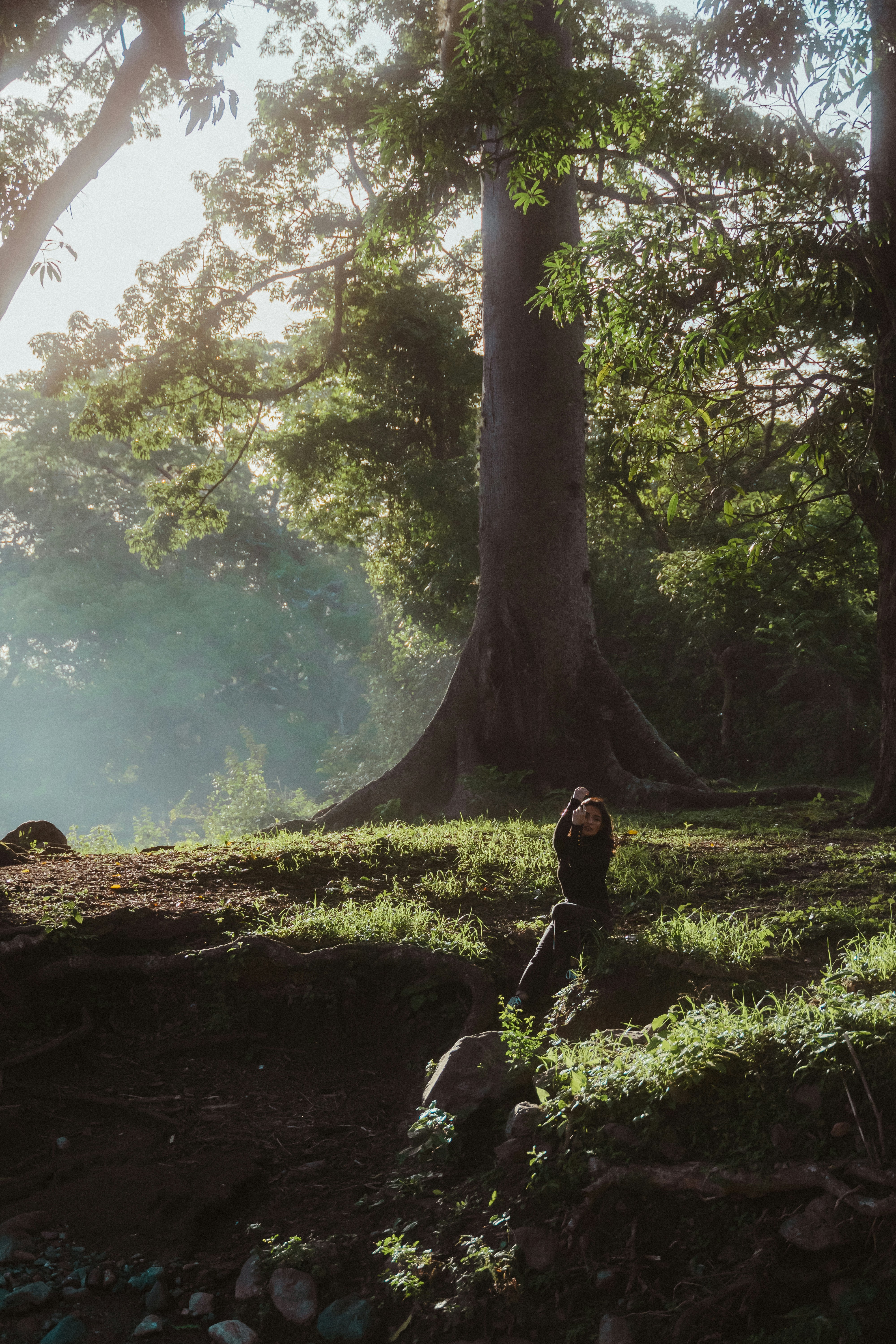 낮 동안 강 근처의 바위에 앉아 있는 검은 재킷을 입은 여자