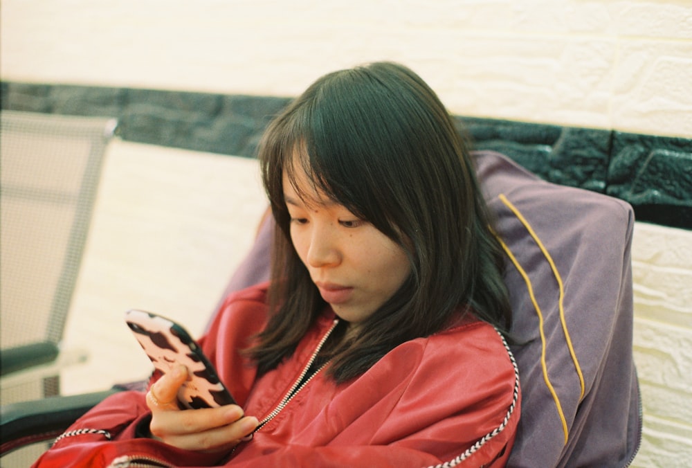 girl in red hoodie holding smartphone