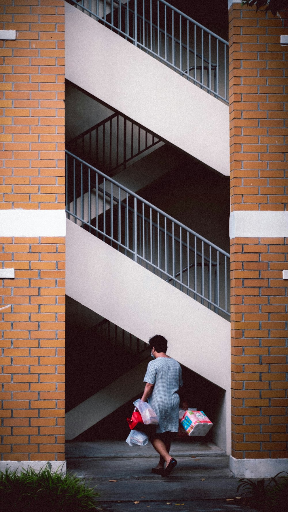 man in white dress shirt walking on brown brick wall