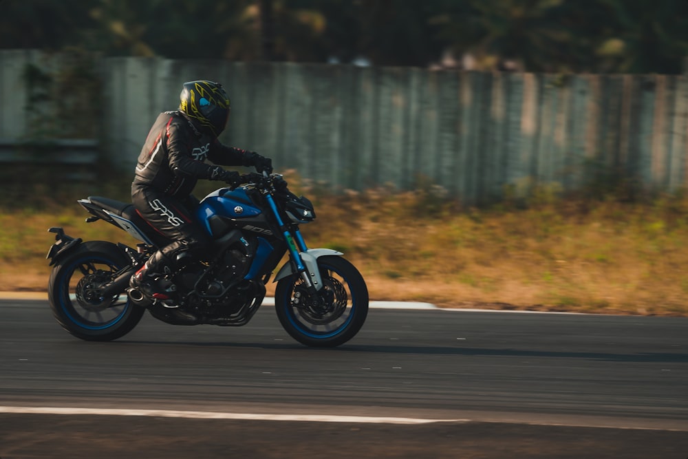 man in black jacket riding blue motorcycle on road during daytime