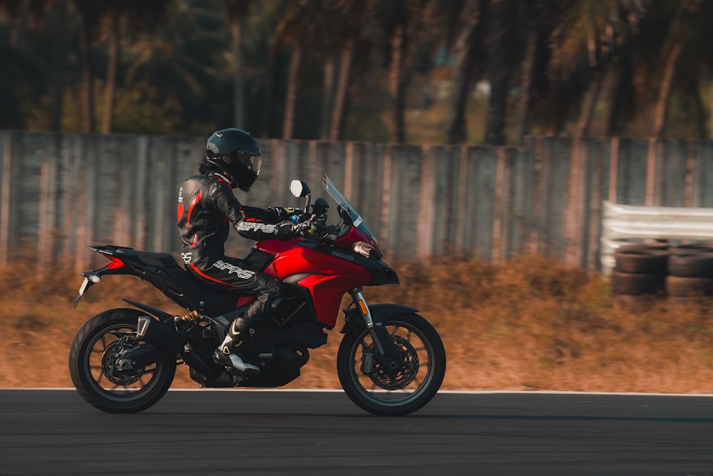 man in black and red motorcycle suit riding on black and red sports bike
