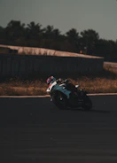 A rider leaning into a sharp turn on a sunny motorcycle track.