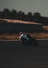 A rider leaning into a sharp turn on a sunny motorcycle track.