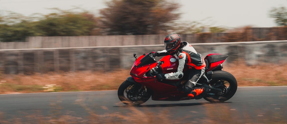 man in black and red motorcycle suit riding on red sports bike