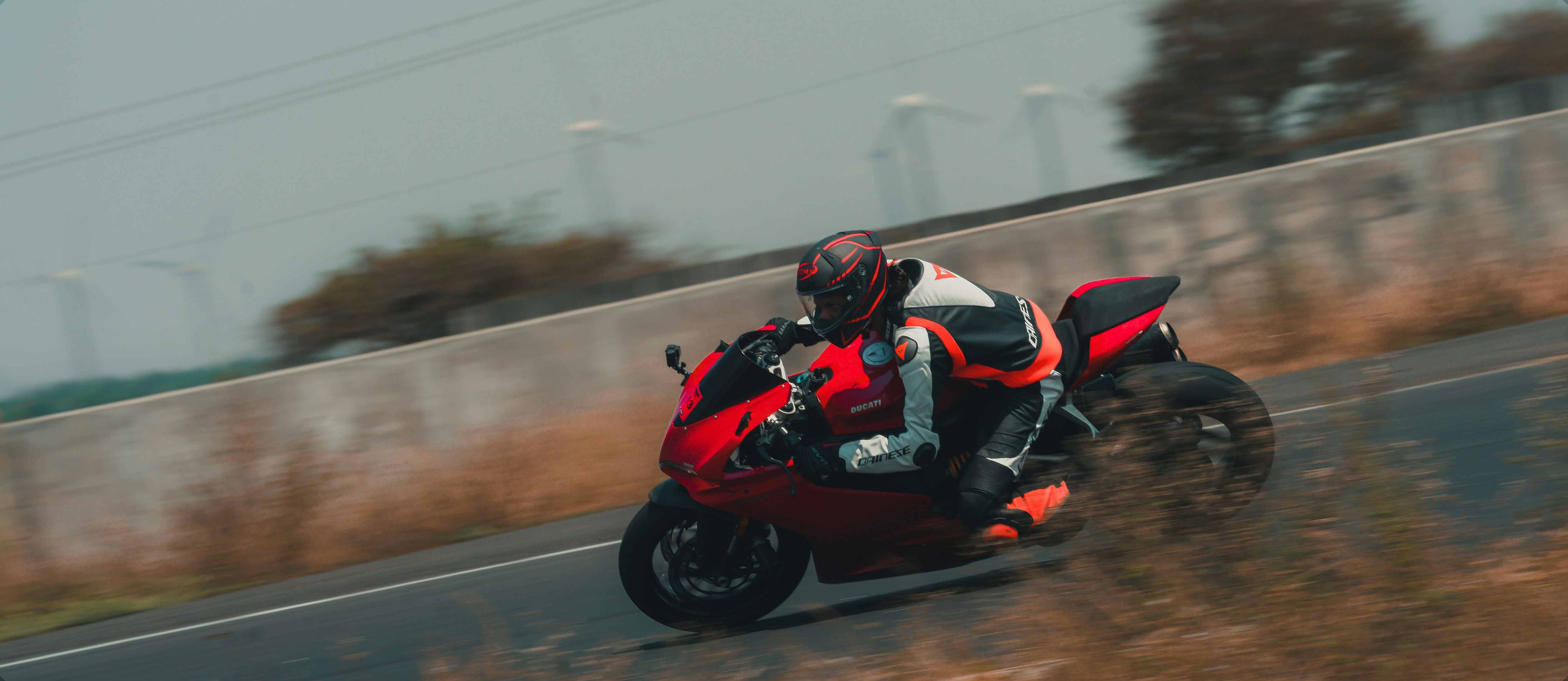 man in red and black motorcycle suit riding on red sports bike