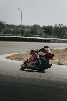 Wide shot of a controlled motorcycle track with riders spaced out, practicing skills in a traffic-free zone.