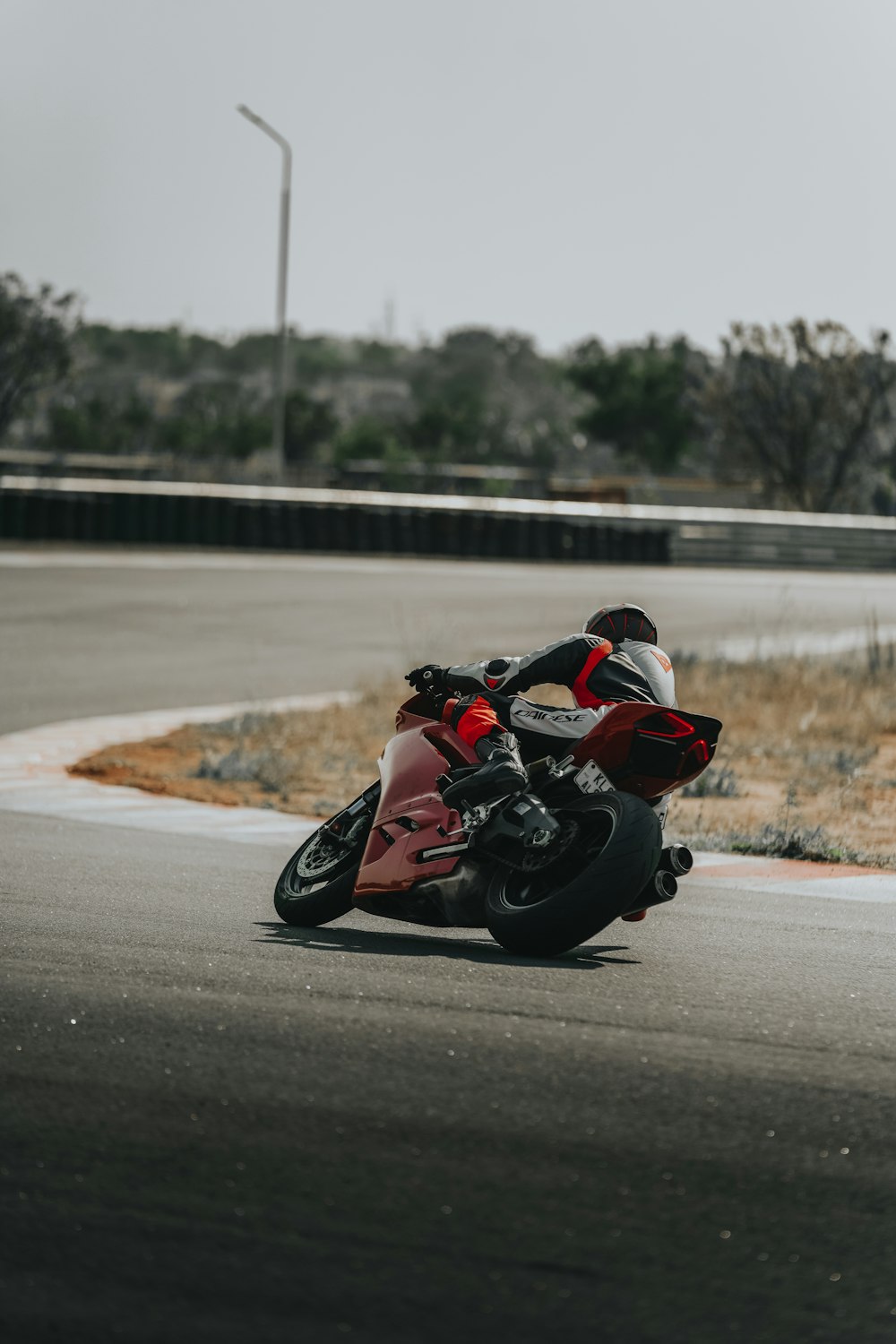 person in red and black motorcycle suit riding on black and white sports bike on road