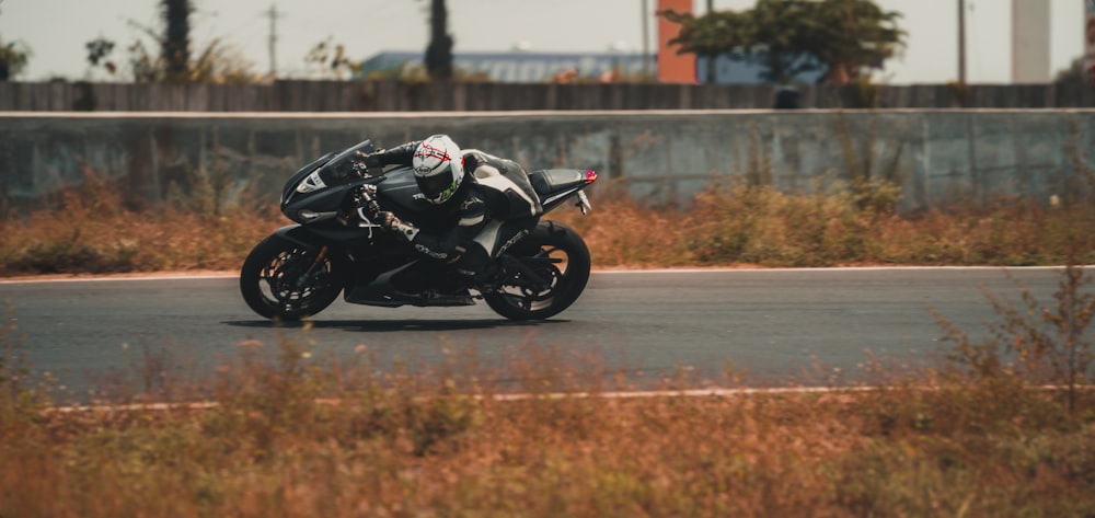 man riding black sports bike on road during daytime