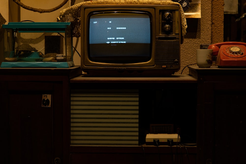 black crt tv on brown wooden tv rack