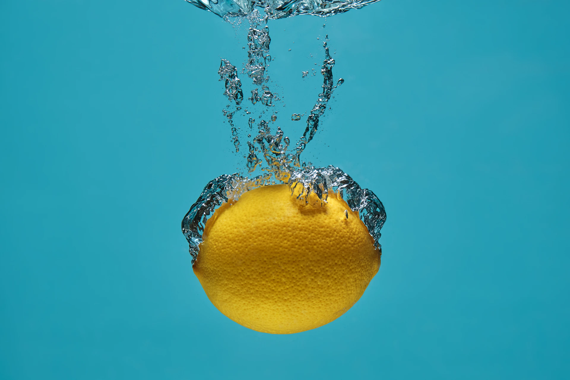 yellow lemon on water with water droplets