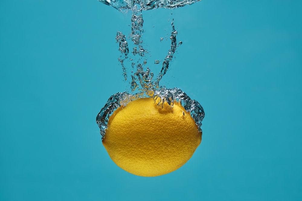 yellow lemon on water with water droplets