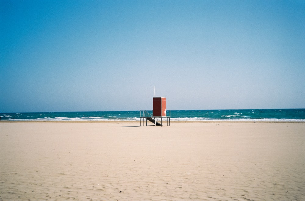 white and red lifeguard tower on beach during daytime