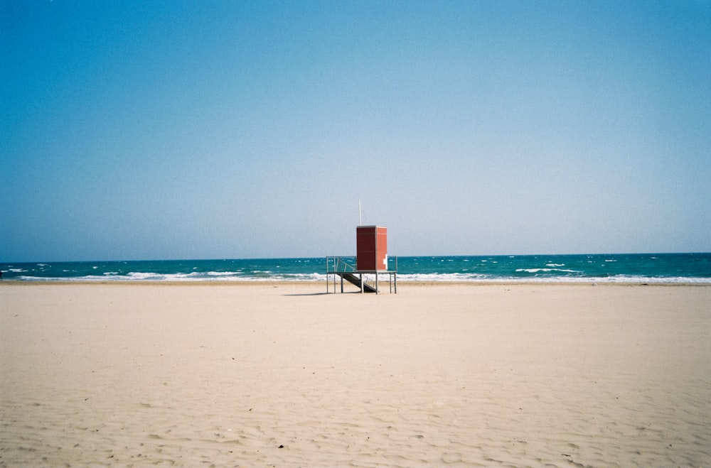 Torre de salvavidas blanca y roja en la playa durante el día