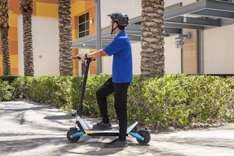 man in blue dress shirt and black pants riding blue and black kick scooter during daytime