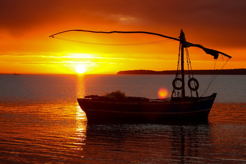 silhouette of boat on sea during sunset