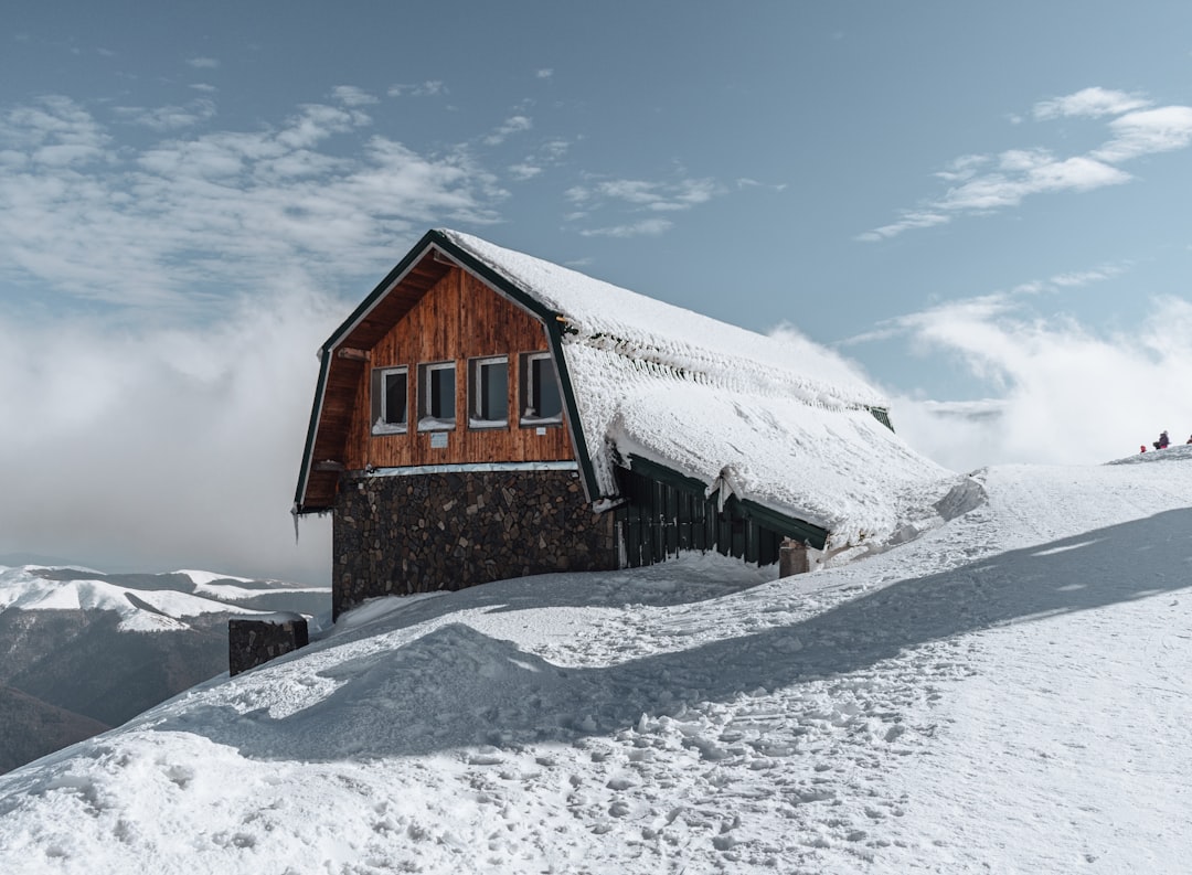 brown wooden house on snow covered ground under blue sky during daytime