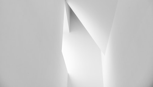 An abstract architectural design with sharp angles and clean lines, showcasing a play of light and shadows on white surfaces.