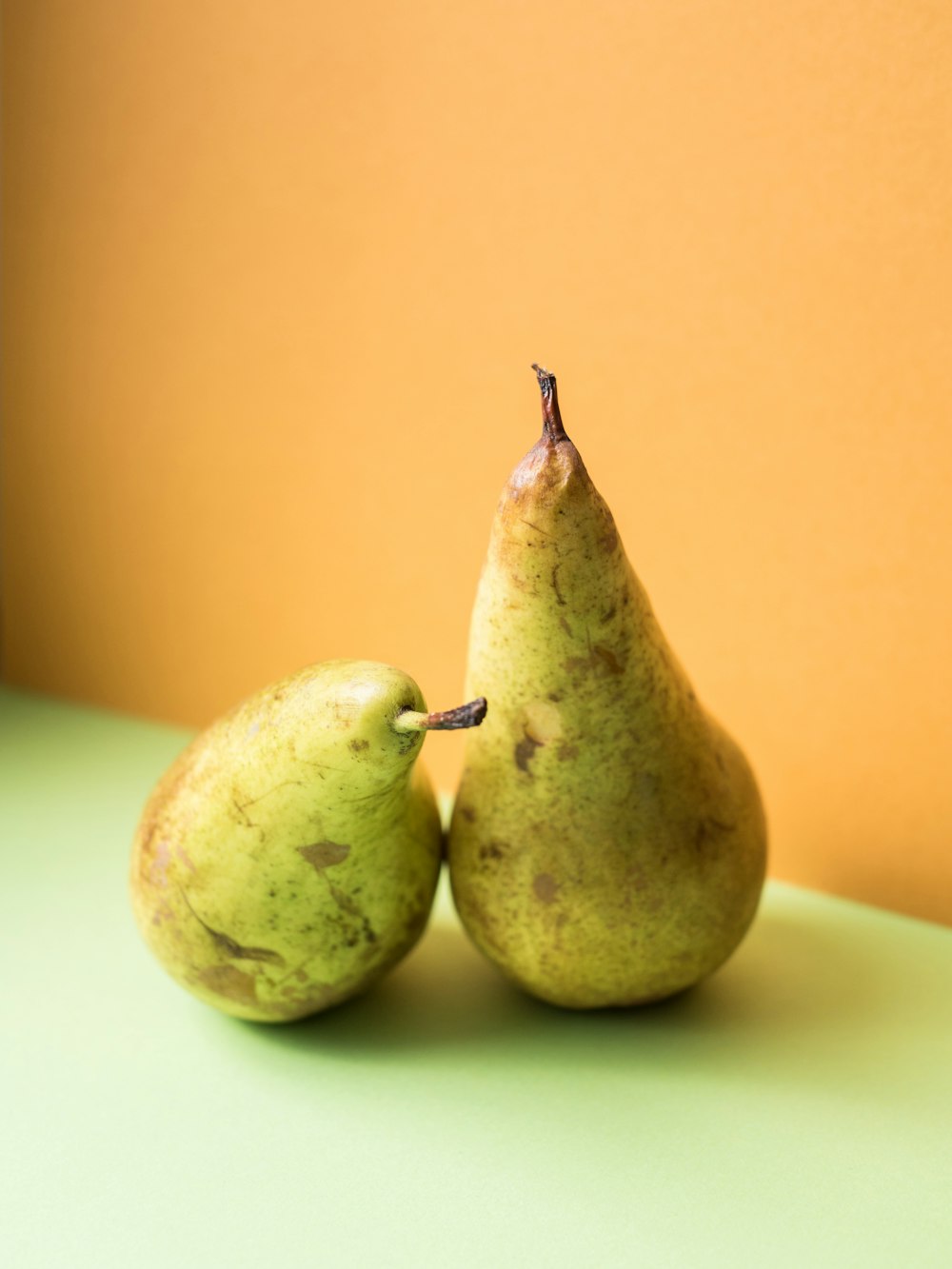 two green fruits on yellow surface