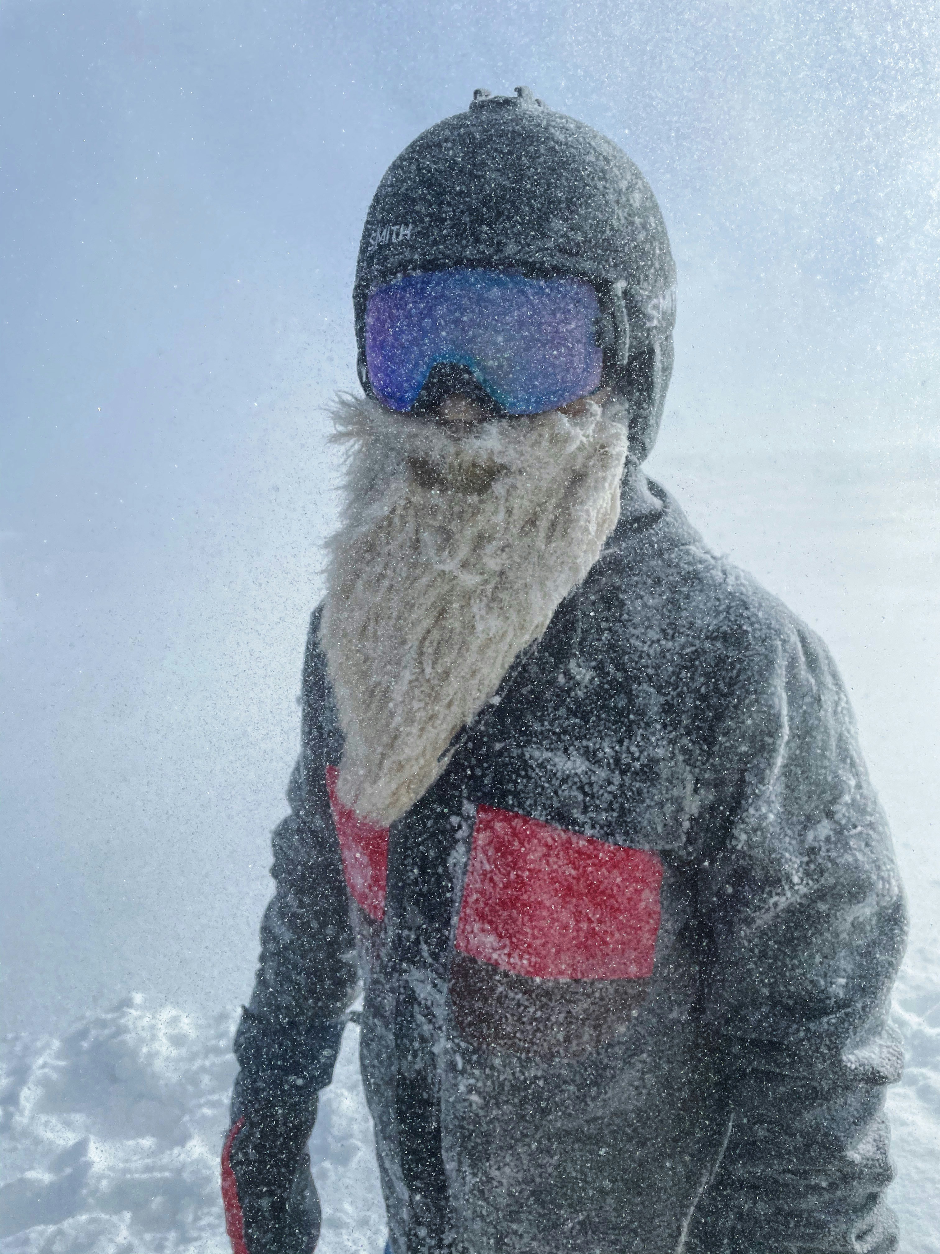 Person im schwarzen Wintermantel, die tagsüber auf schneebedecktem Boden steht
