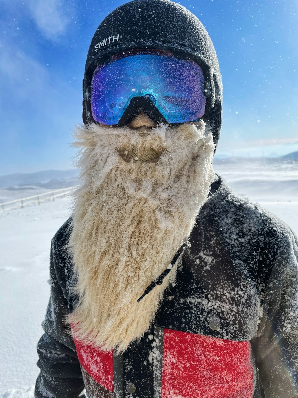 person in black and red jacket wearing blue goggles