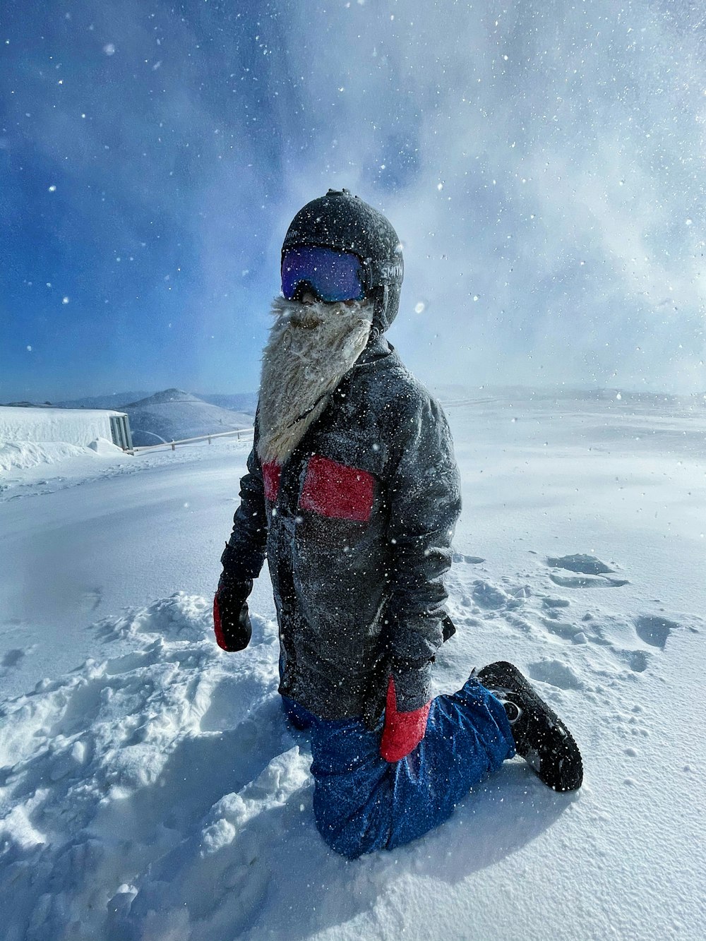 person in gray winter jacket and blue pants standing on snow covered ground during daytime