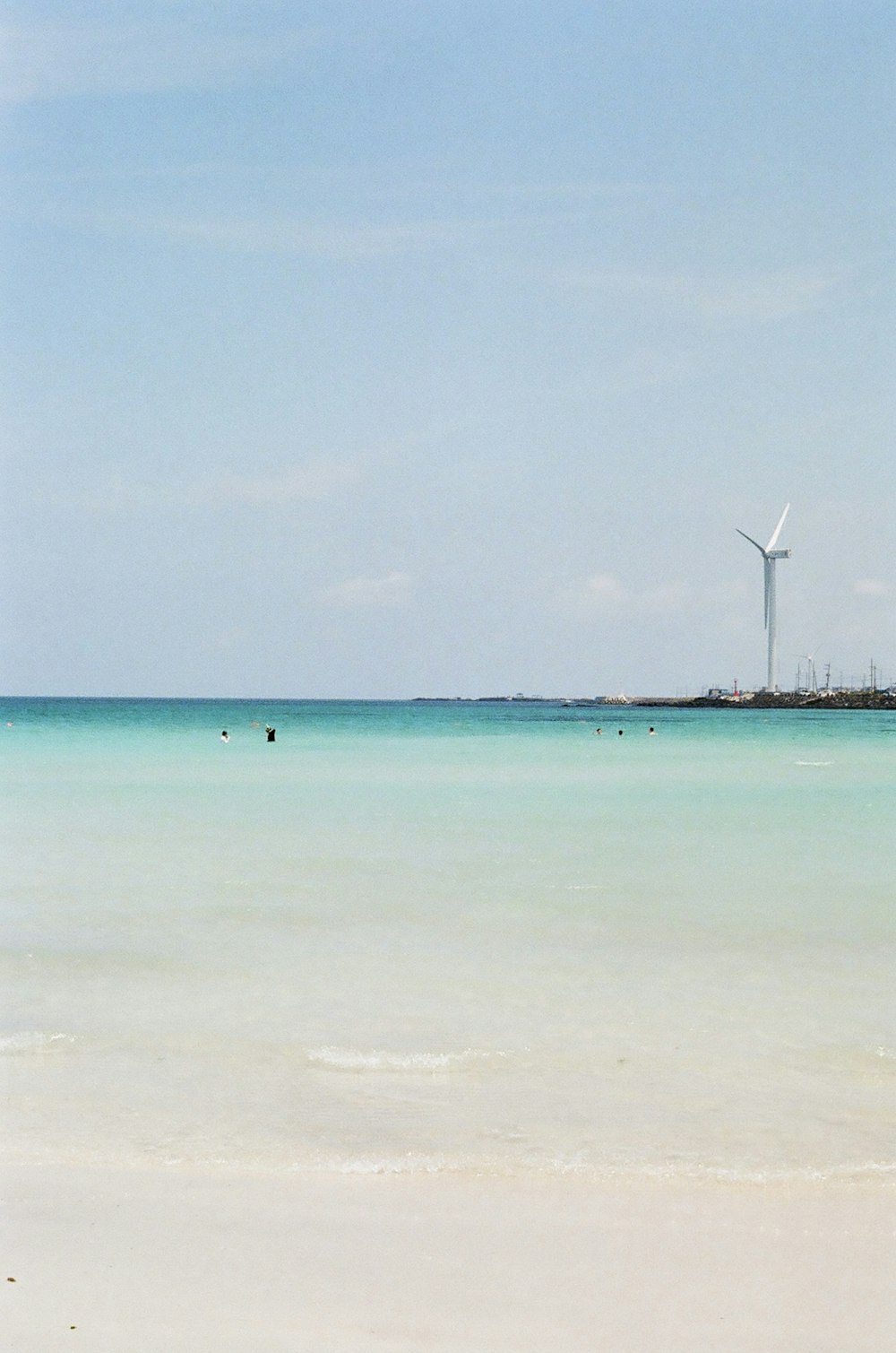 white wind turbines on green sea under blue sky during daytime