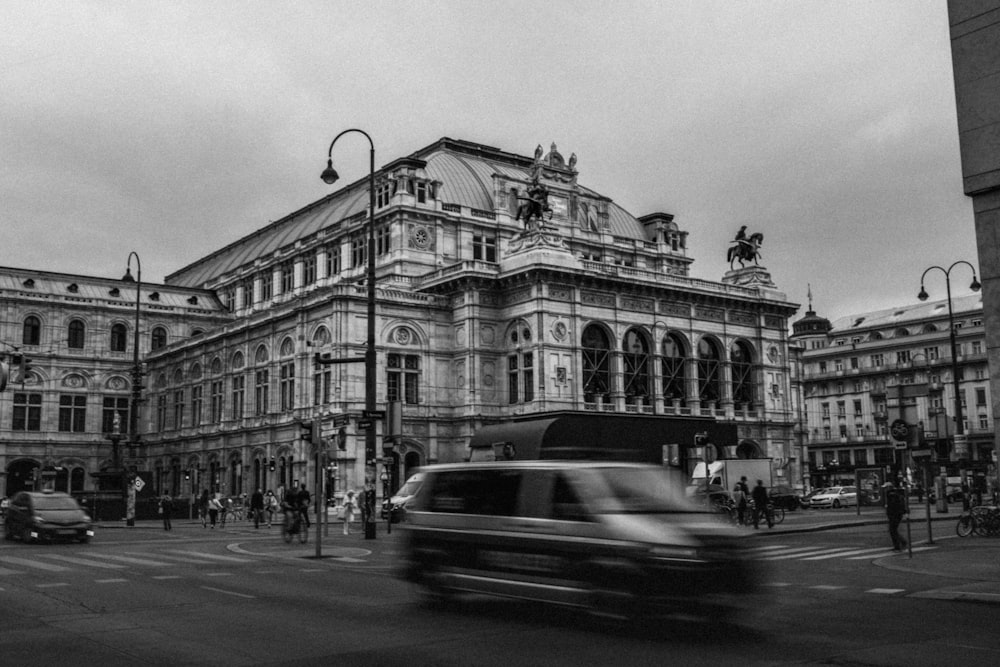 grayscale photo of cars on road near building