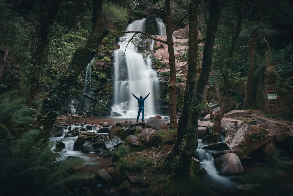 person standing on rock near waterfalls during daytime