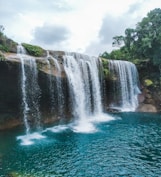 waterfalls near green trees during daytime