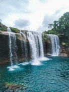 waterfalls near green trees during daytime