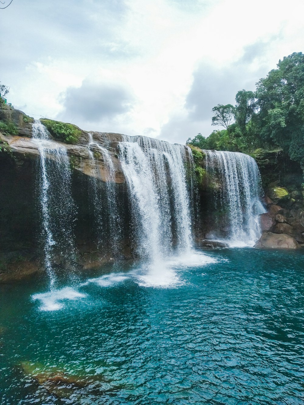 waterfalls near green trees during daytime