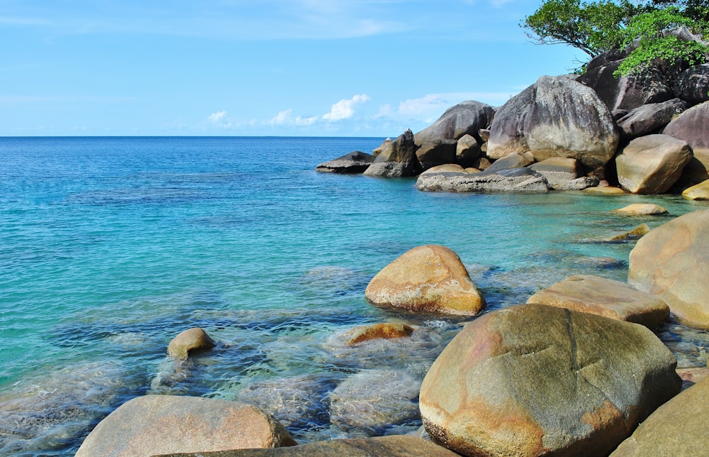 brown rocks on blue sea under blue sky during daytime