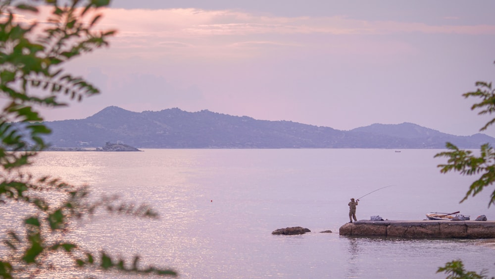 person standing on rock near body of water during daytime