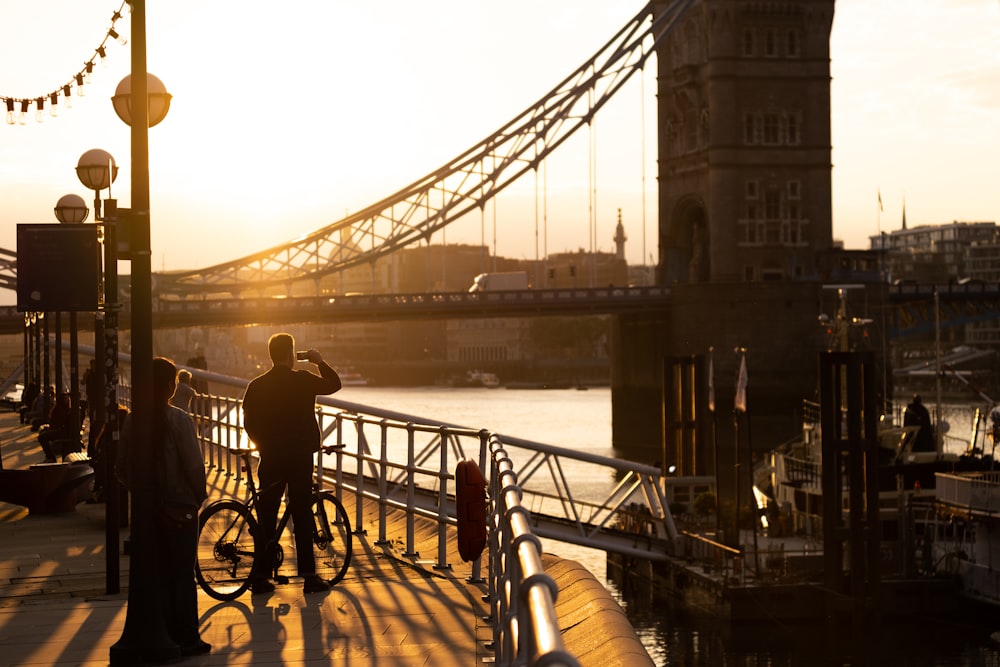 man in black jacket and pants standing on bridge during daytime