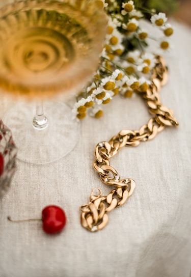 Close-up of a champagne gold necklace resting delicately on soft ivory fabric.