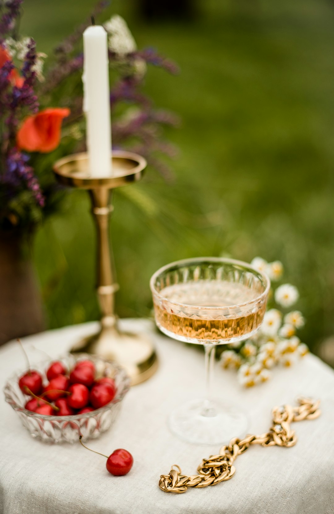 gold colored footed glass with white candle on white table