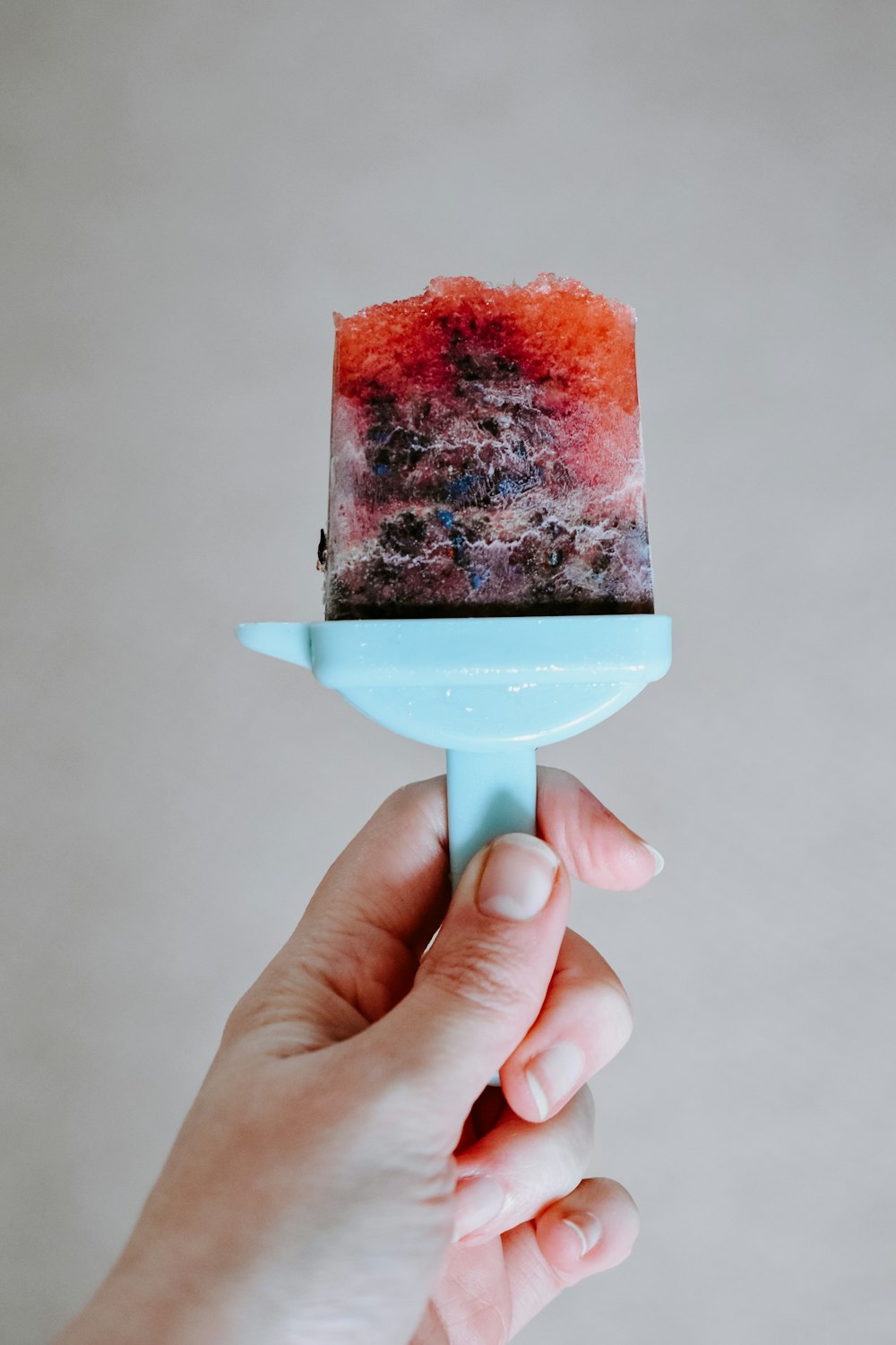 person holding ice cream with red powder