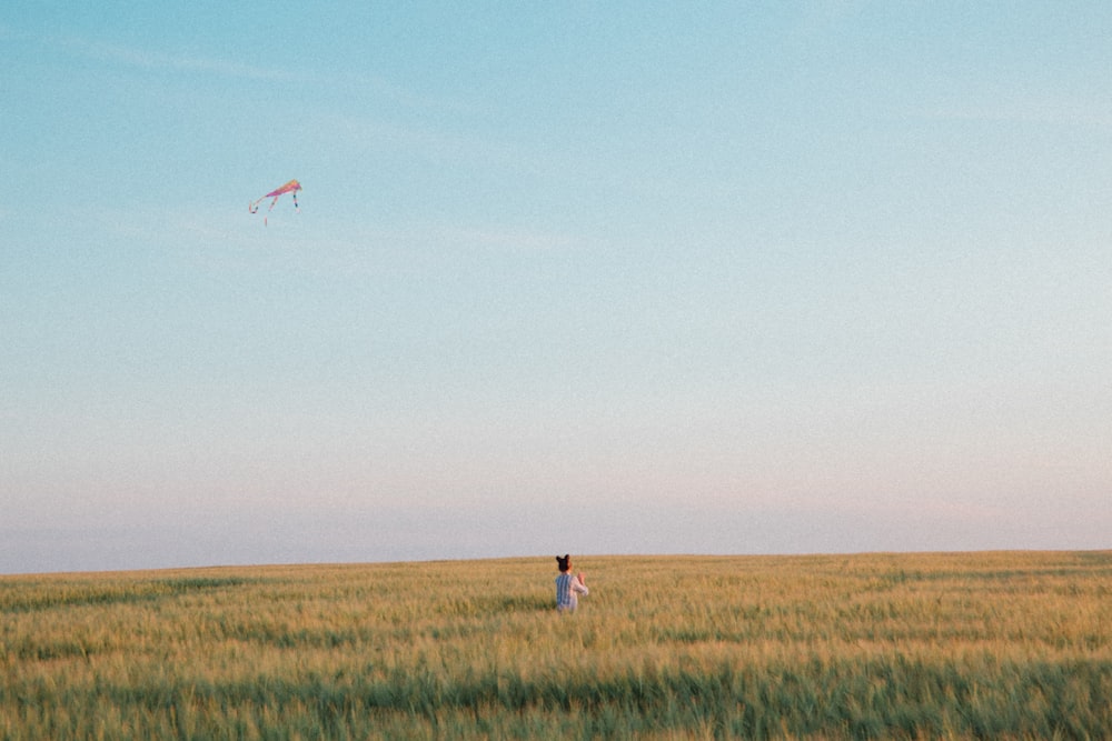 man in white shirt and blue denim jeans standing on green grass field during daytime