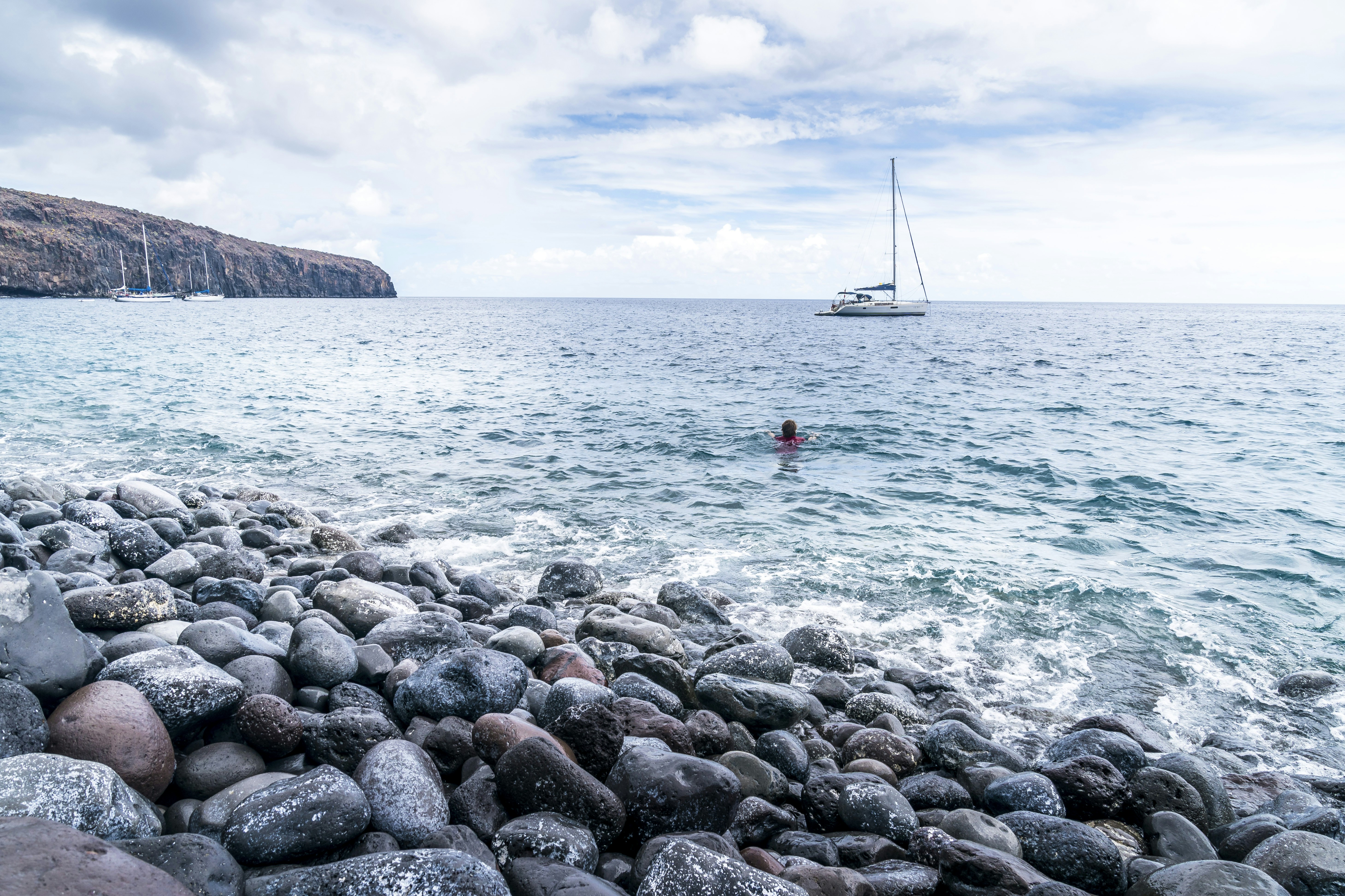 Un bañista en una playa de La Gomera, en las islas Canarias. De fondo, un barco navegando. 