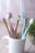 A bright bathroom scene featuring a modern toothbrush holder with colorful toothbrushes and a fresh plant.