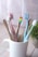 A bright bathroom scene featuring a modern toothbrush holder with colorful toothbrushes and a fresh plant.