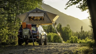 man in green jacket sitting on black and yellow camping chair near tent during daytime