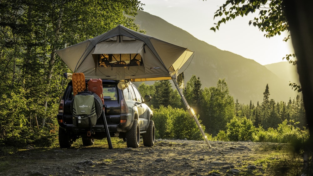 man in green jacket sitting on black and yellow camping chair near tent during daytime