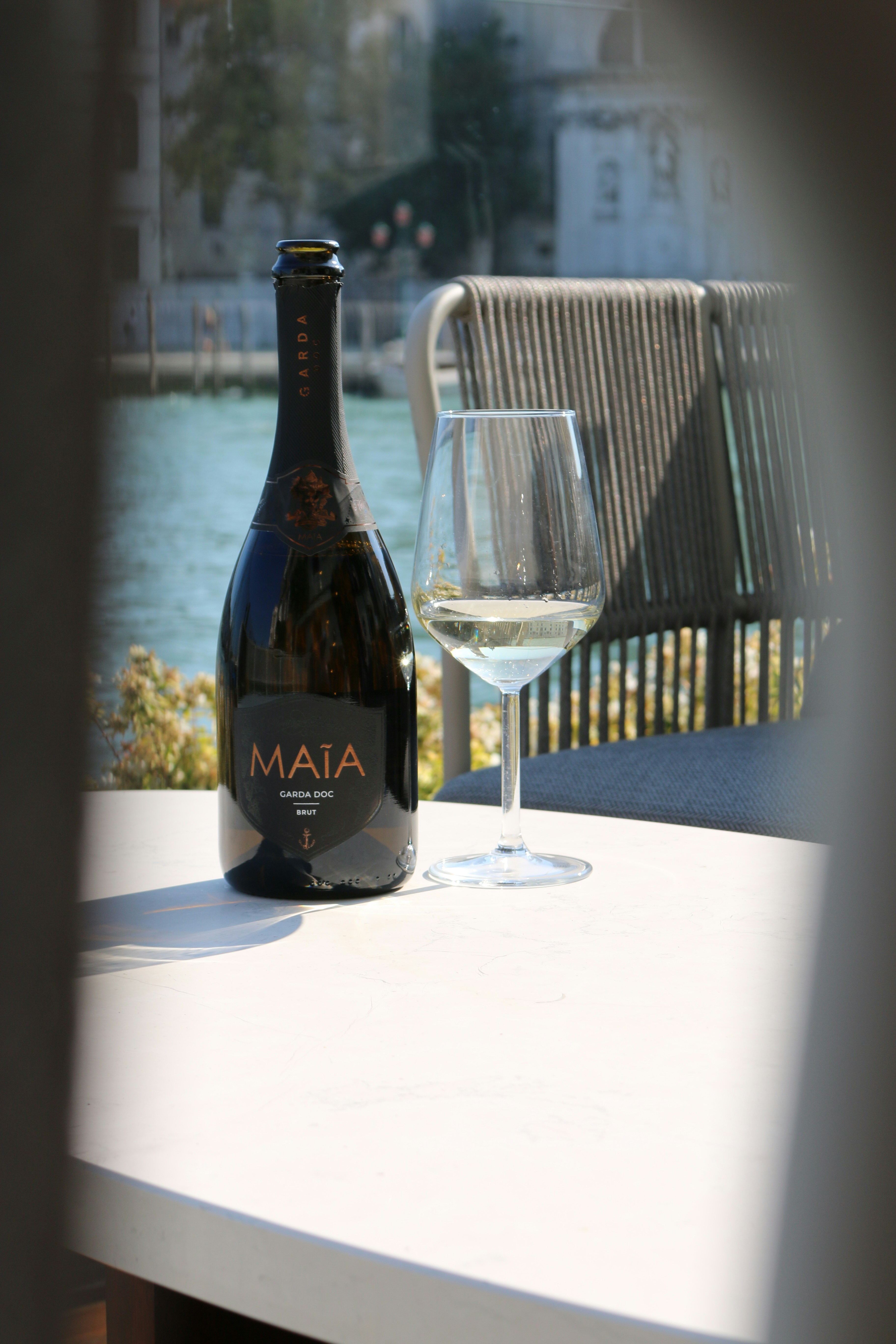 black glass bottle beside clear wine glass on white table