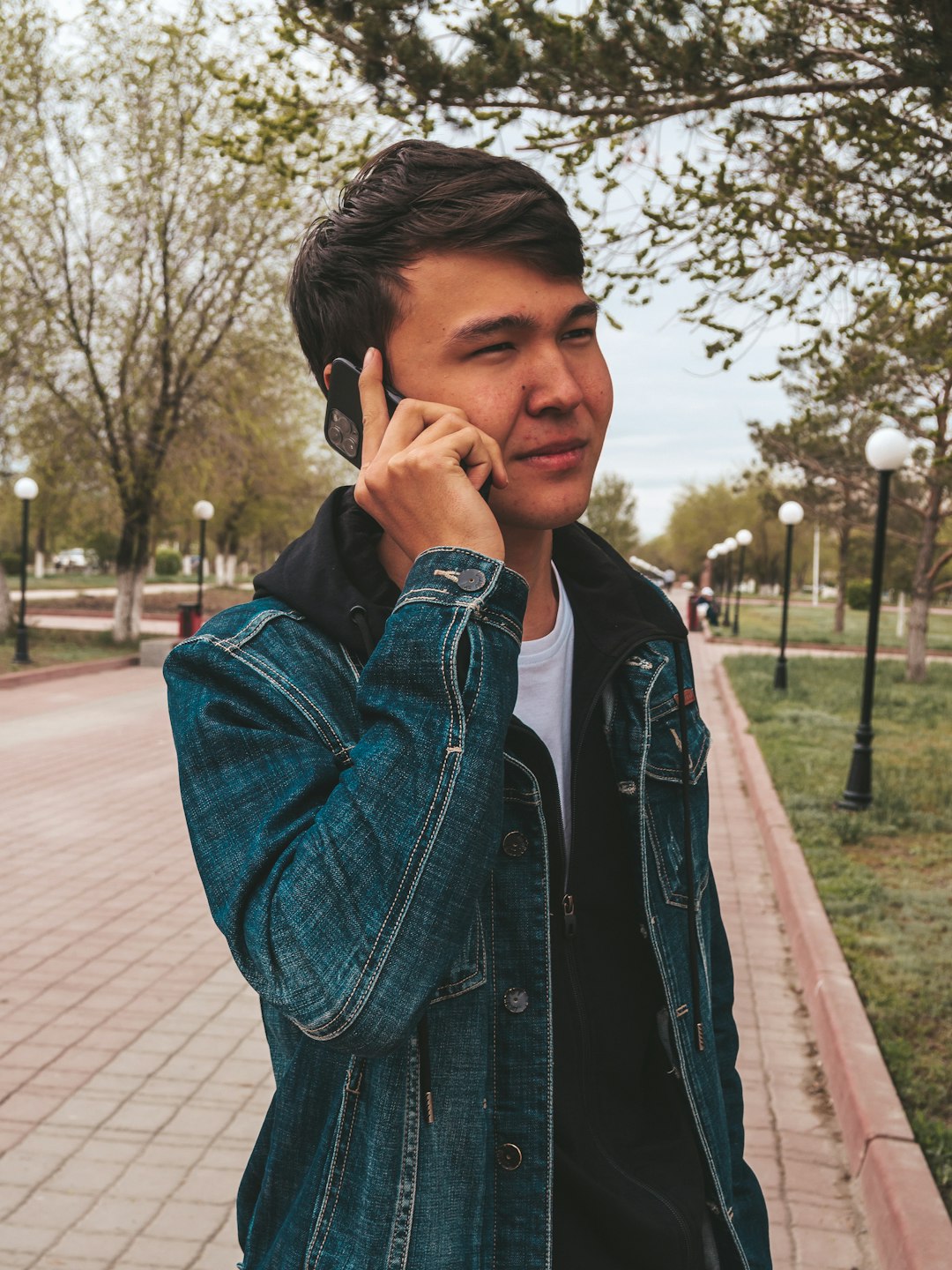 man in blue denim jacket standing on sidewalk during daytime