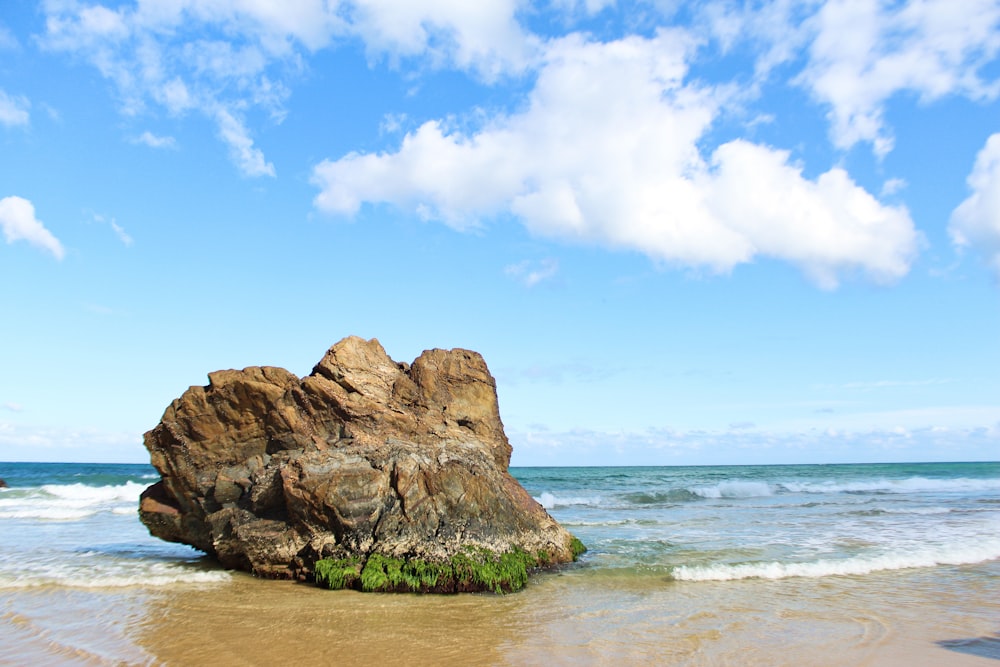 brown rock formation on body of water under blue sky during daytime