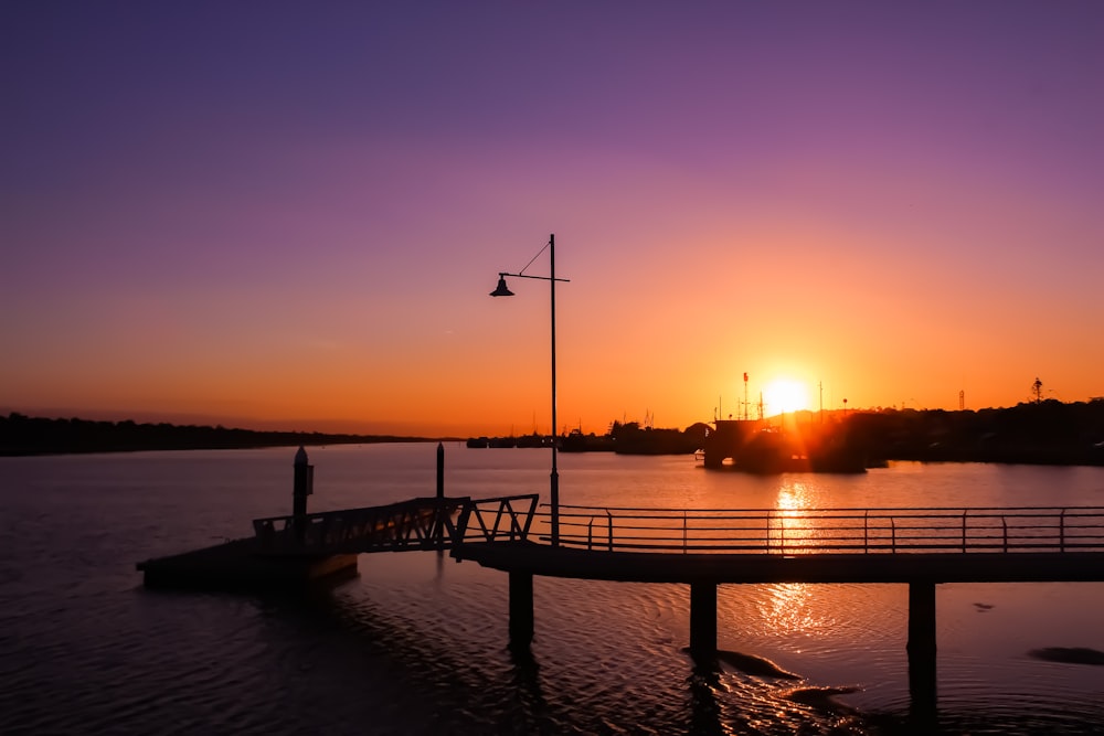 silhouette of a person standing on a dock during sunset