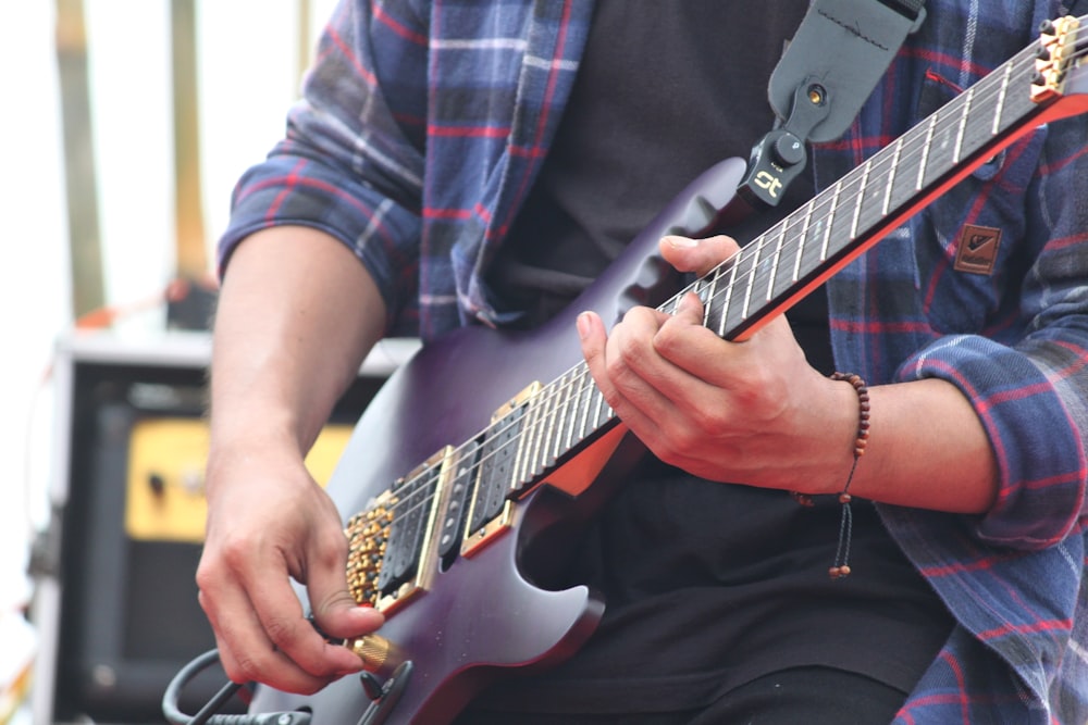 person playing electric guitar during daytime